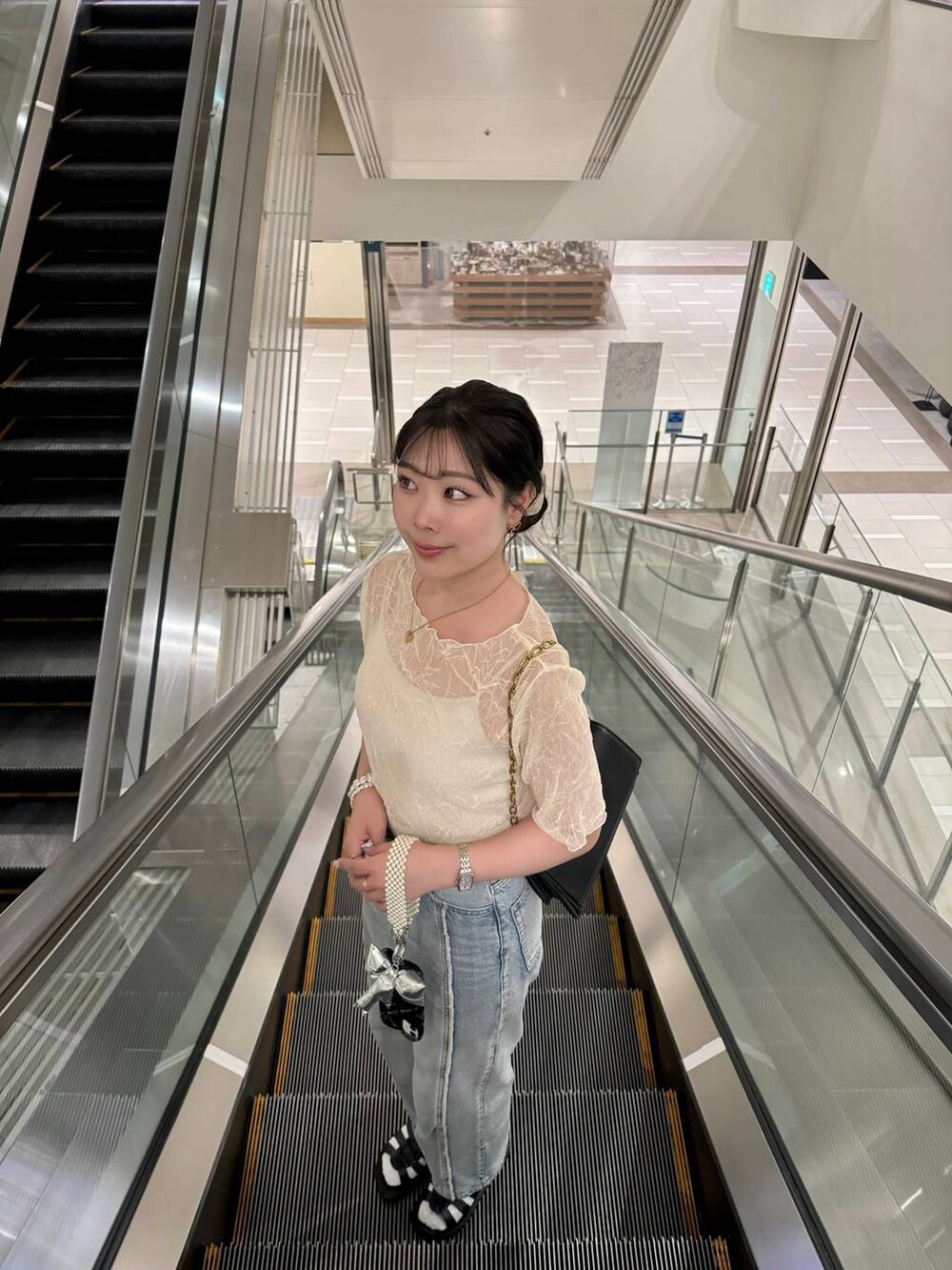 ホワイト系のTシャツ/カットソー、ブラック系のスニーカー、ブルー系のデニムパンツを着用したレディースの夏コーディネートの2枚目の写真