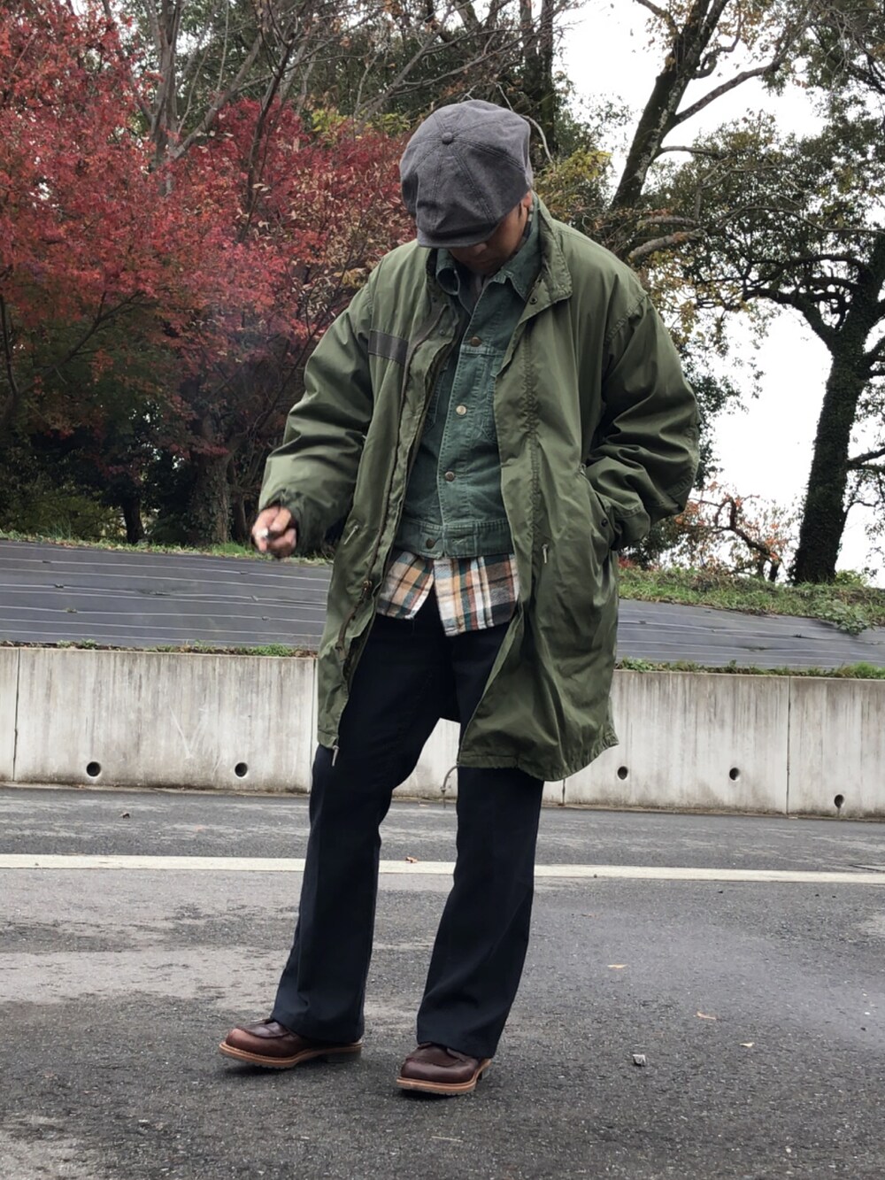 ブラウン系のブーツ、ブラック系のスラックス、グリーン系のモッズコートを着用したメンズの秋コーディネートの2枚目の写真
