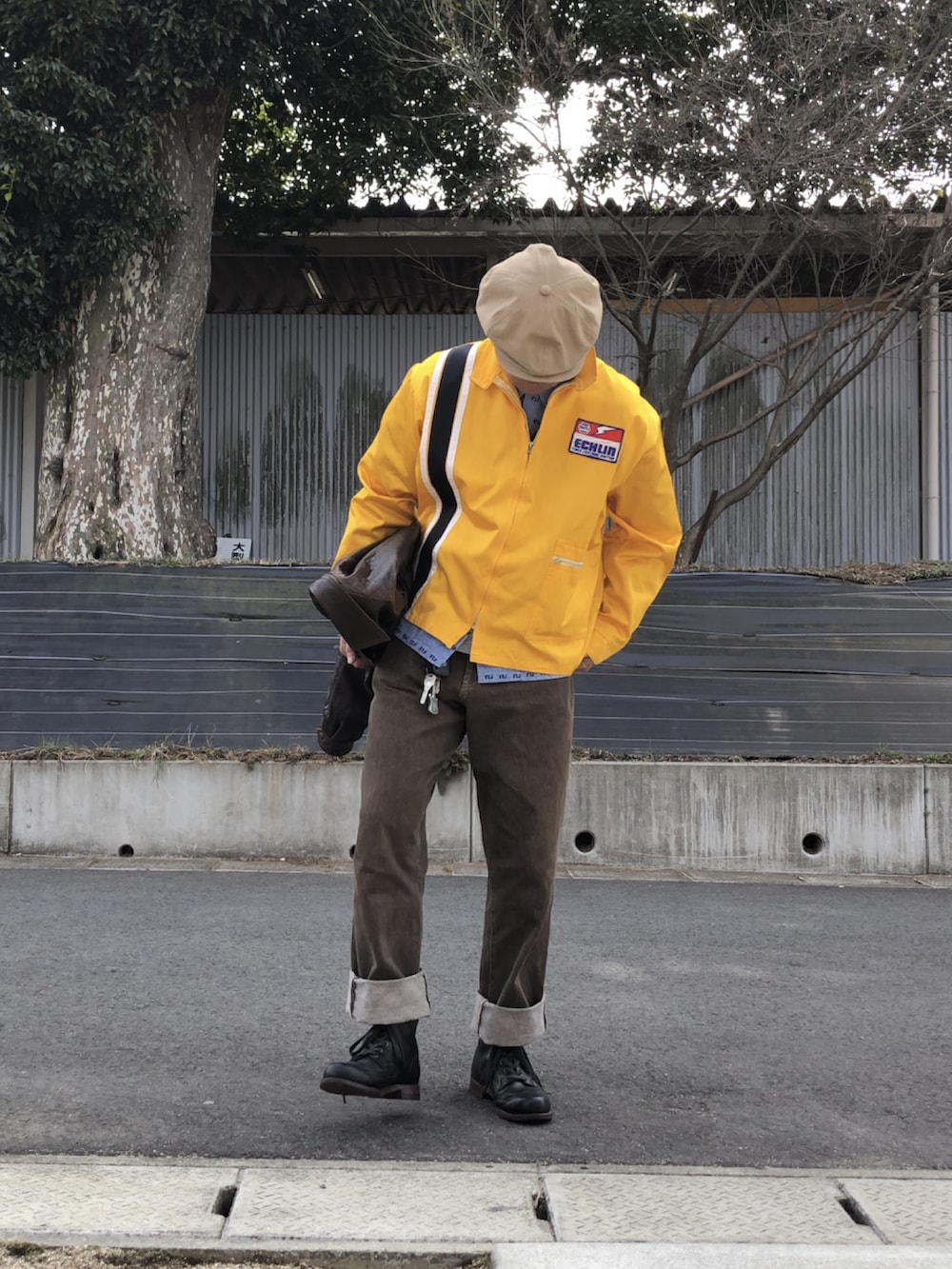 ブラック系のブーツ、ブラウン系のデニムパンツ、イエロー系のナイロンジャケットを着用したメンズの冬コーディネートの2枚目の写真