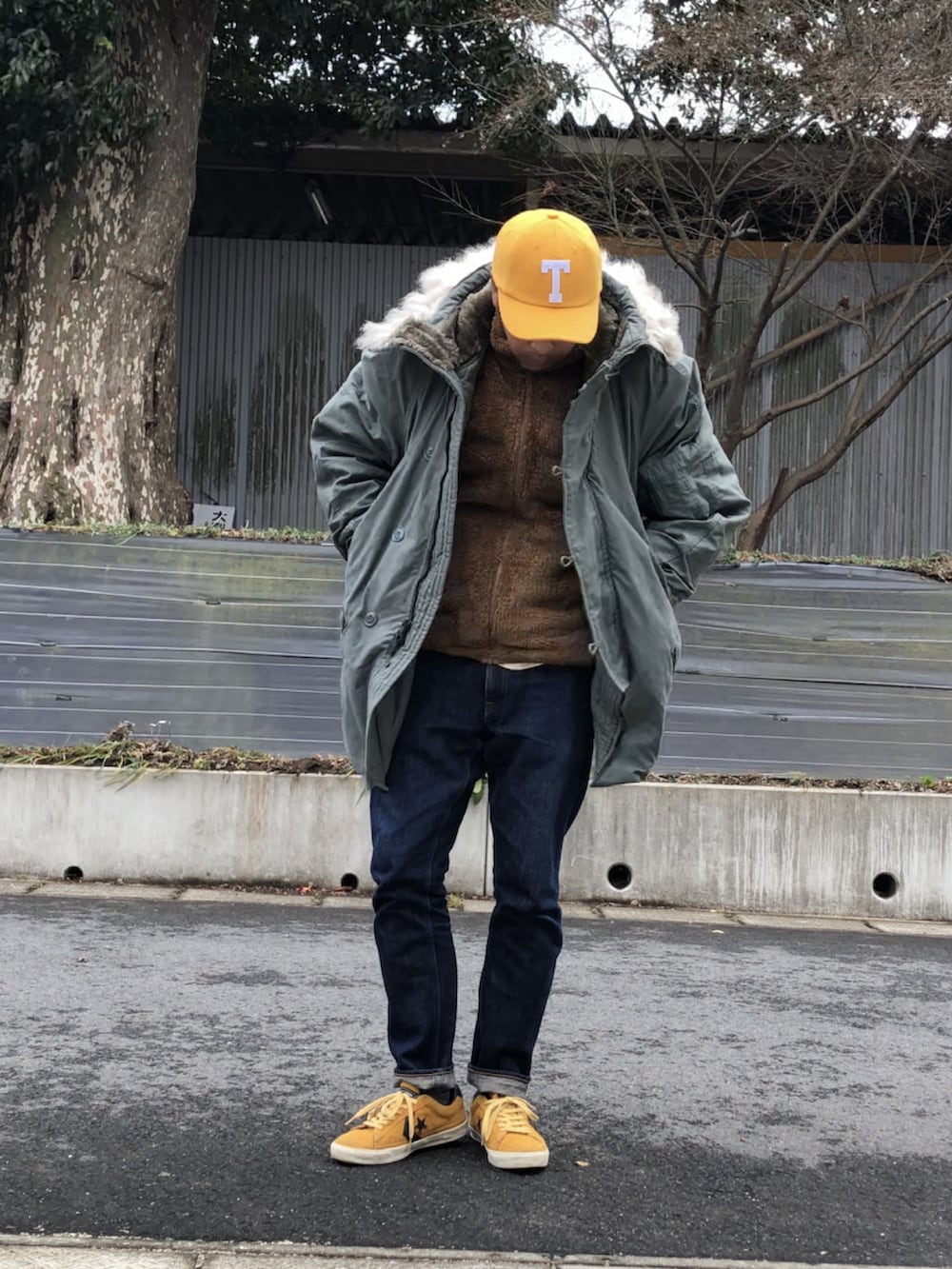 イエロー系のスニーカー、ブルー系のデニムパンツ、グリーン系のミリタリージャケットを着用したメンズの冬コーディネートの2枚目の写真