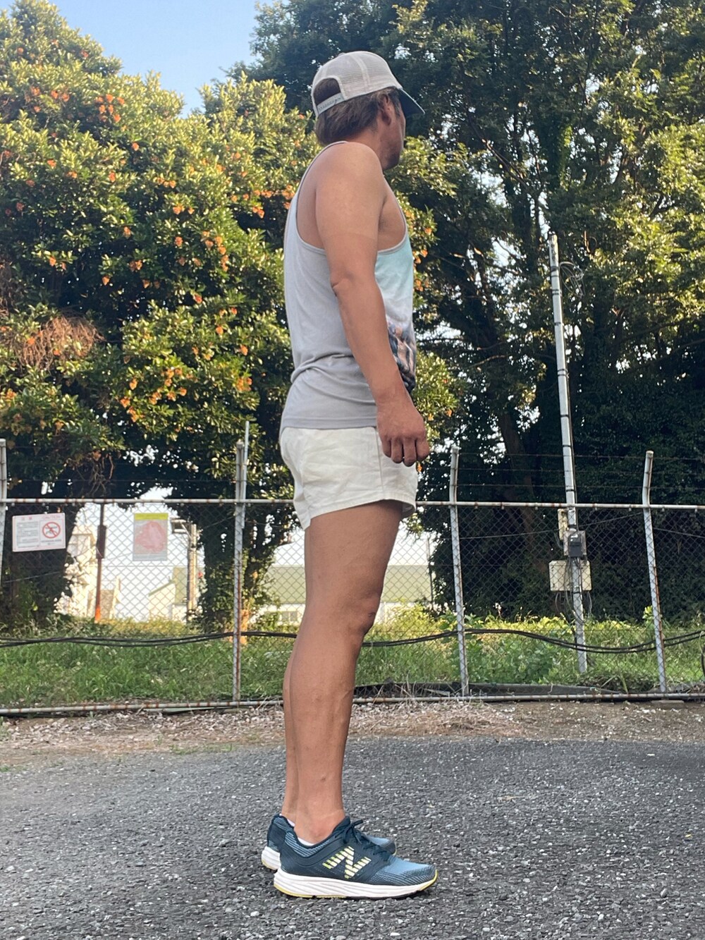 ブルー系のスニーカー、ブルー系のタンクトップ、ホワイト系のパンツを着用したメンズの夏コーディネートの4枚目の写真