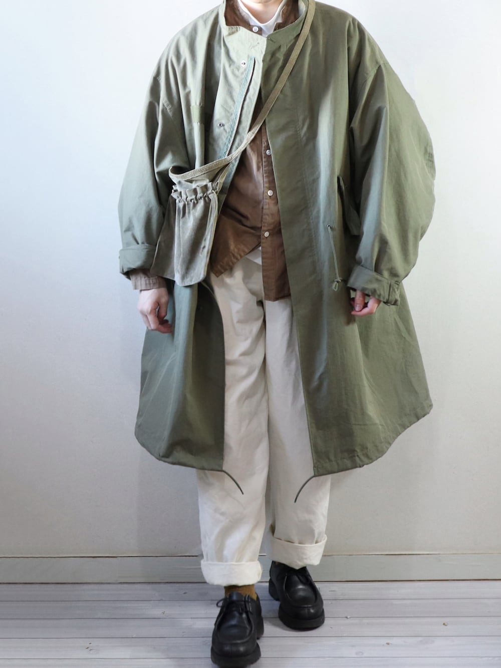 グリーン系のモッズコート、ブラウン系のシャツ/ブラウス、グリーン系のショルダーバッグを着用したメンズの冬コーディネートの3枚目の写真