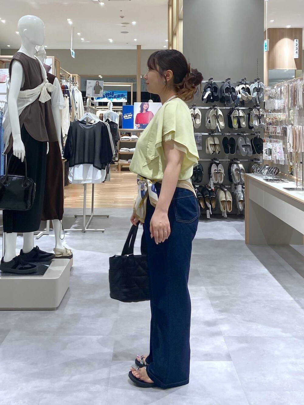 ブラック系のトートバッグ、イエロー系のTシャツ/カットソー、ブルー系のデニムパンツを着用したレディースの夏コーディネートの2枚目の写真