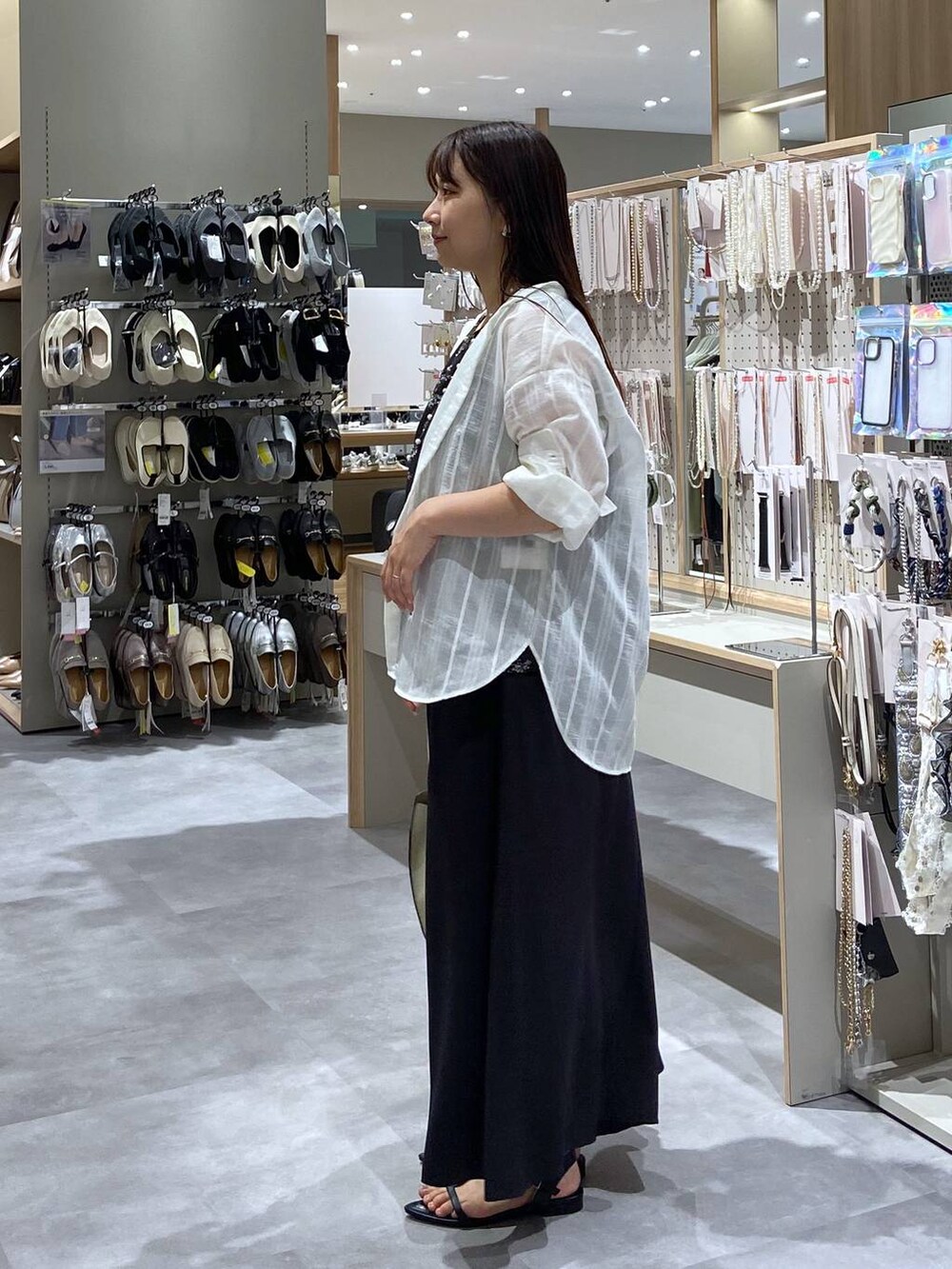 ホワイト系のショルダーバッグ、ホワイト系のシャツ/ブラウス、ブラック系のサンダルを着用したレディースの夏コーディネートの2枚目の写真