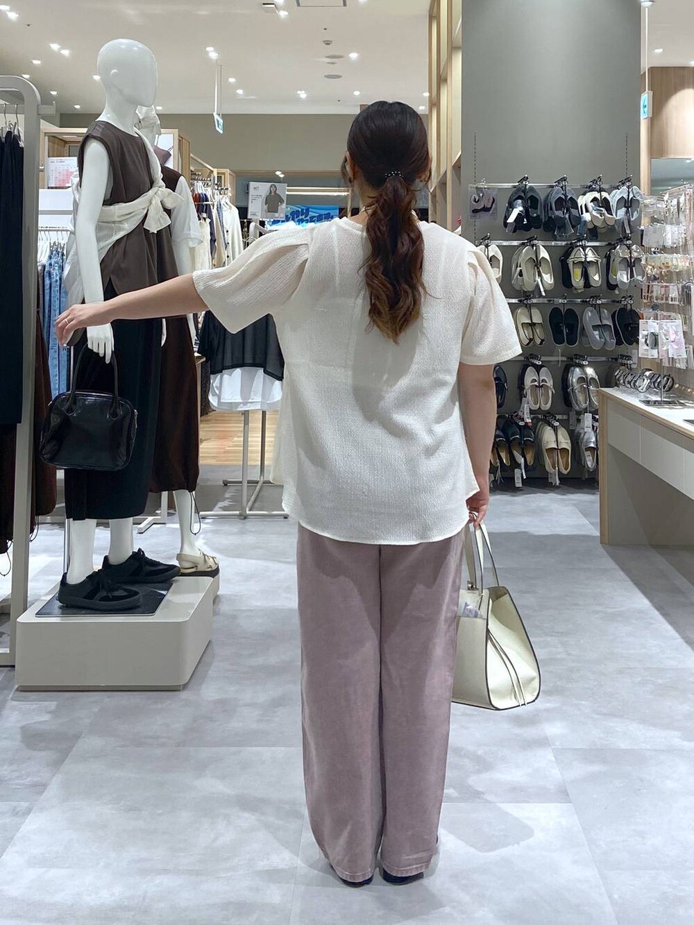 ホワイト系のショルダーバッグ、ベージュ系のTシャツ/カットソー、ブラック系のサンダルを着用したレディースの夏コーディネートの3枚目の写真