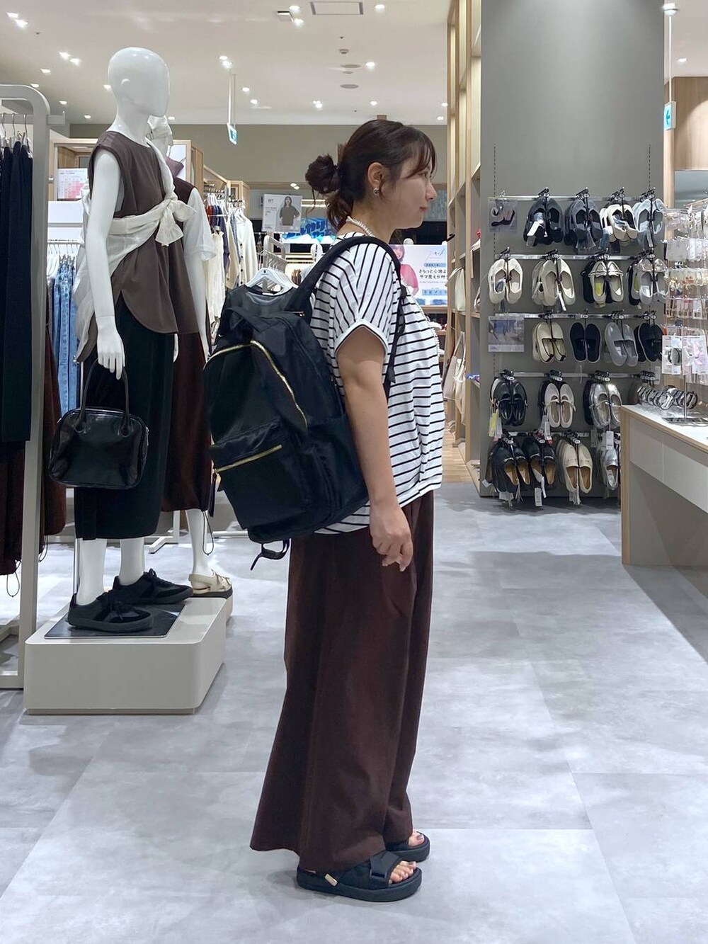 ブラック系のバックパック/リュック、ブラック系のサンダル、ホワイト系のTシャツ/カットソーを着用したレディースの夏コーディネートの4枚目の写真