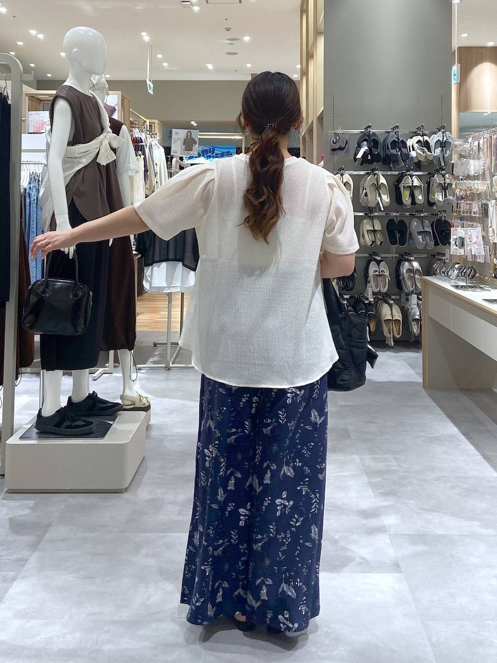 ブラック系のトートバッグ、ベージュ系のTシャツ/カットソー、ブラック系のサンダルを着用したレディースの夏コーディネートの3枚目の写真
