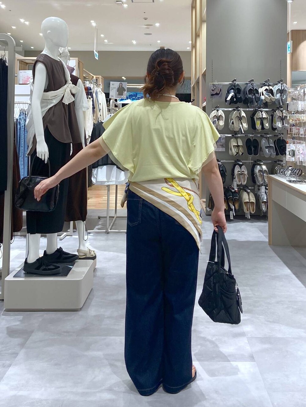 ブラック系のトートバッグ、イエロー系のTシャツ/カットソー、ブルー系のデニムパンツを着用したレディースの夏コーディネートの3枚目の写真