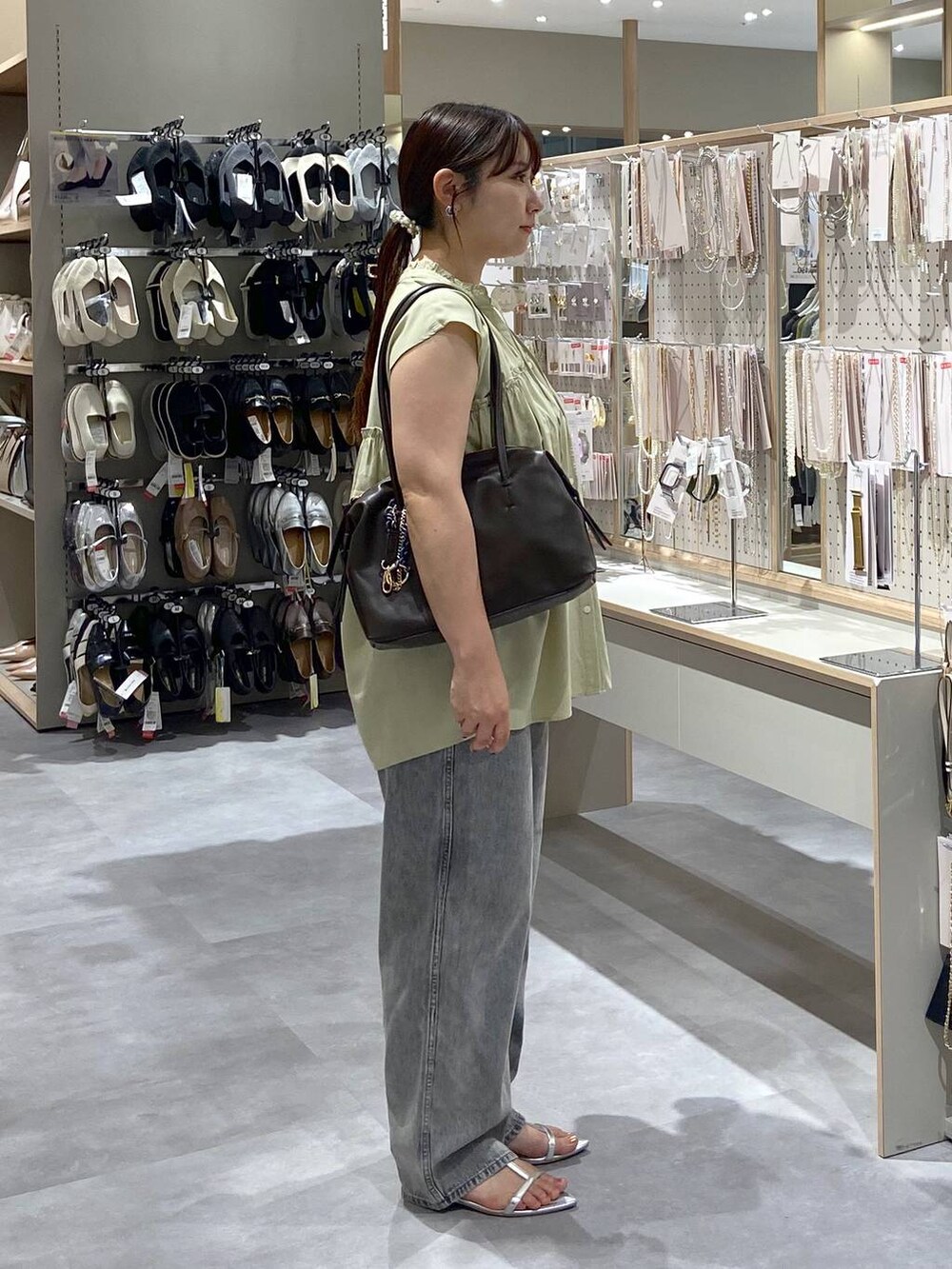 グレー系のデニムパンツ、シルバー系のサンダル、ブラウン系のボストンバッグを着用したレディースの夏コーディネートの4枚目の写真