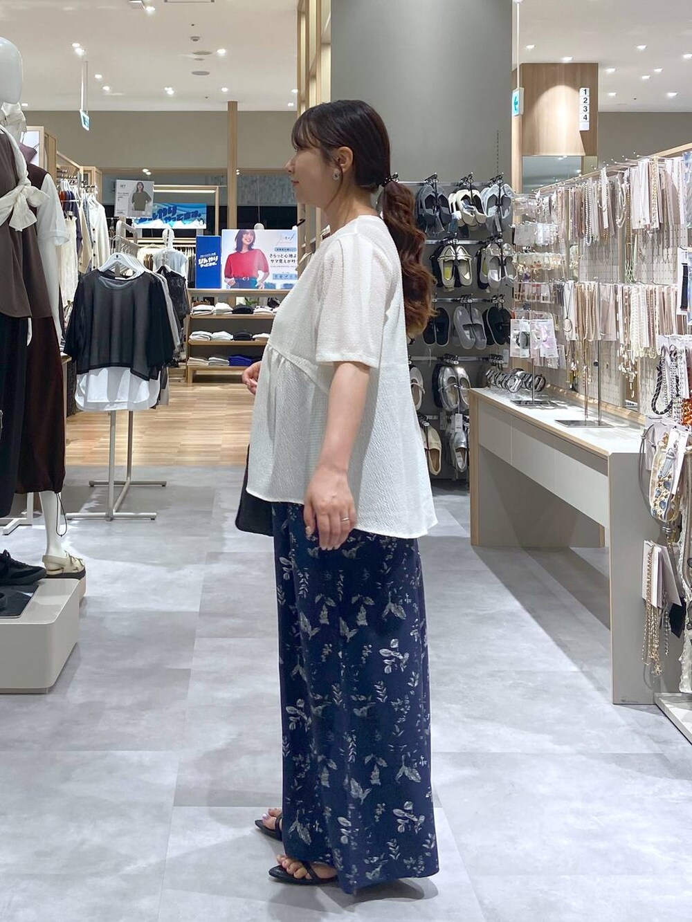 ブラック系のトートバッグ、ベージュ系のTシャツ/カットソー、ブラック系のサンダルを着用したレディースの夏コーディネートの2枚目の写真