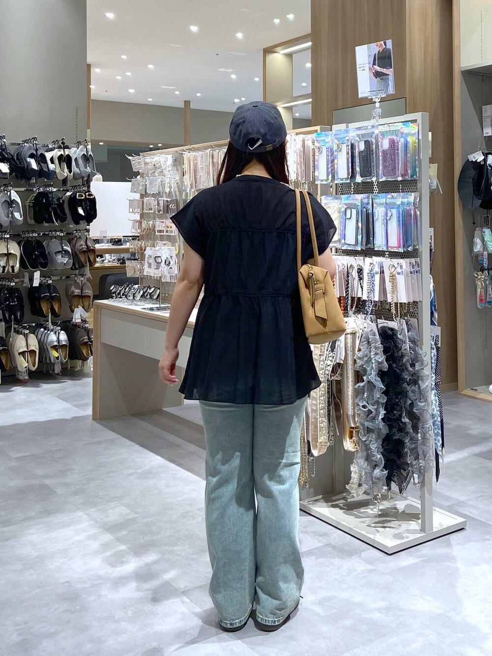 ブラック系のシャツ/ブラウス、ベージュ系のボストンバッグ、ブルー系のデニムパンツを着用したレディースの夏コーディネートの3枚目の写真