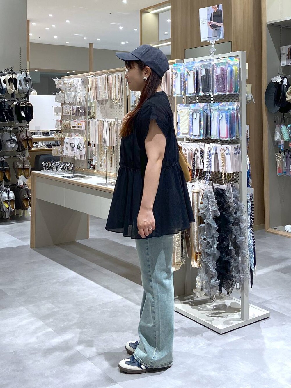 ブラック系のシャツ/ブラウス、ベージュ系のボストンバッグ、ブルー系のデニムパンツを着用したレディースの夏コーディネートの2枚目の写真