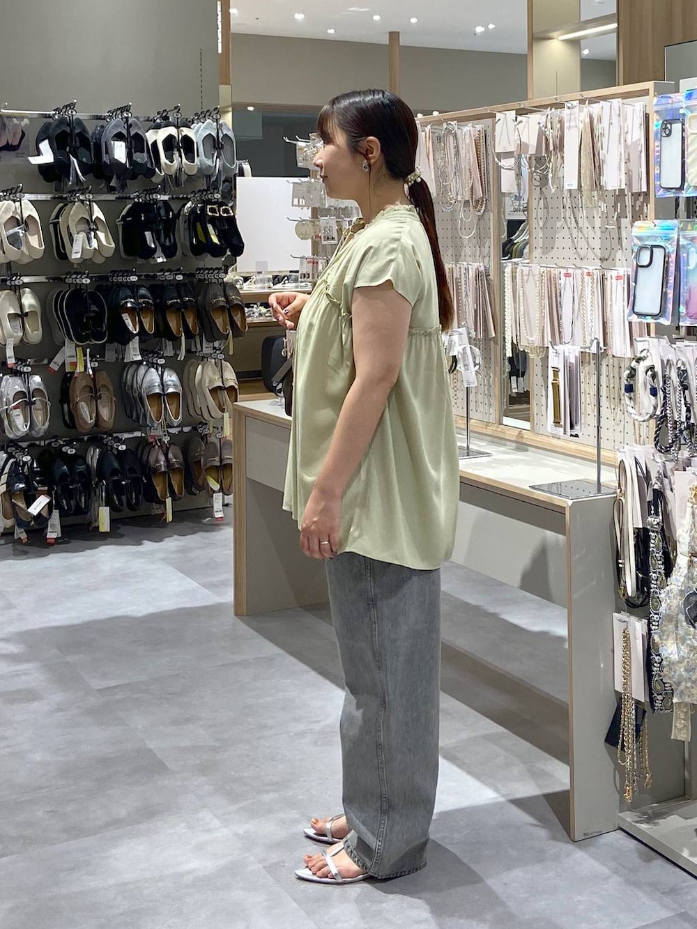 グレー系のデニムパンツ、シルバー系のサンダル、ブラウン系のボストンバッグを着用したレディースの夏コーディネートの2枚目の写真