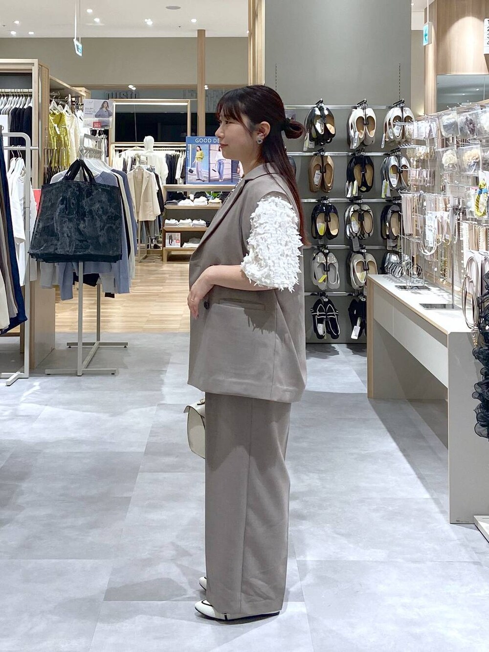 ホワイト系のショルダーバッグ、ベージュ系のベスト、ホワイト系のパンプスを着用したレディースの春コーディネートの2枚目の写真