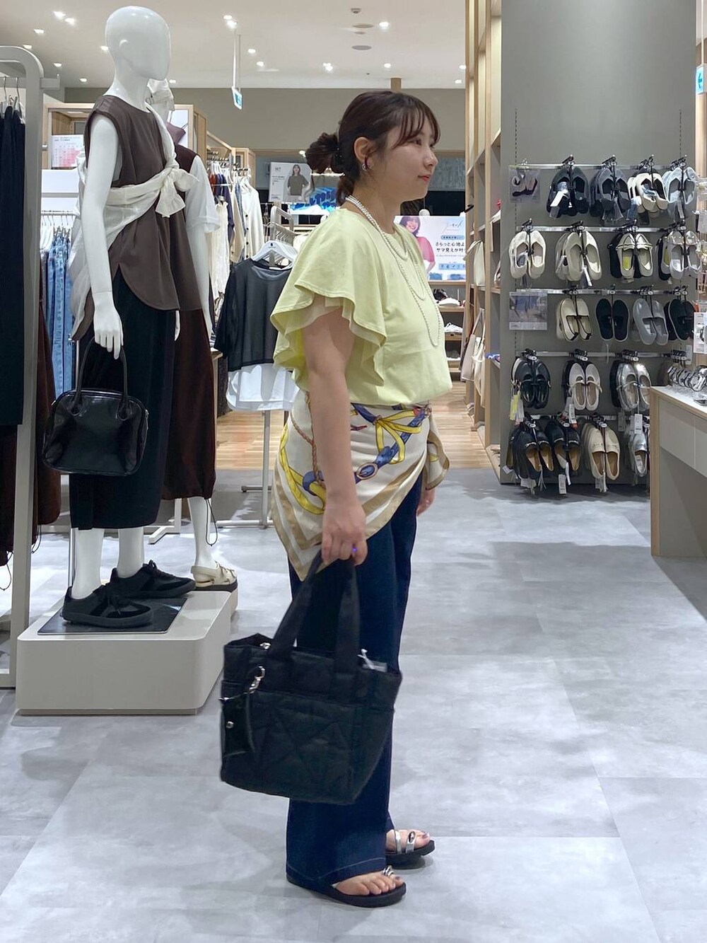 ブラック系のトートバッグ、イエロー系のTシャツ/カットソー、ブルー系のデニムパンツを着用したレディースの夏コーディネートの4枚目の写真