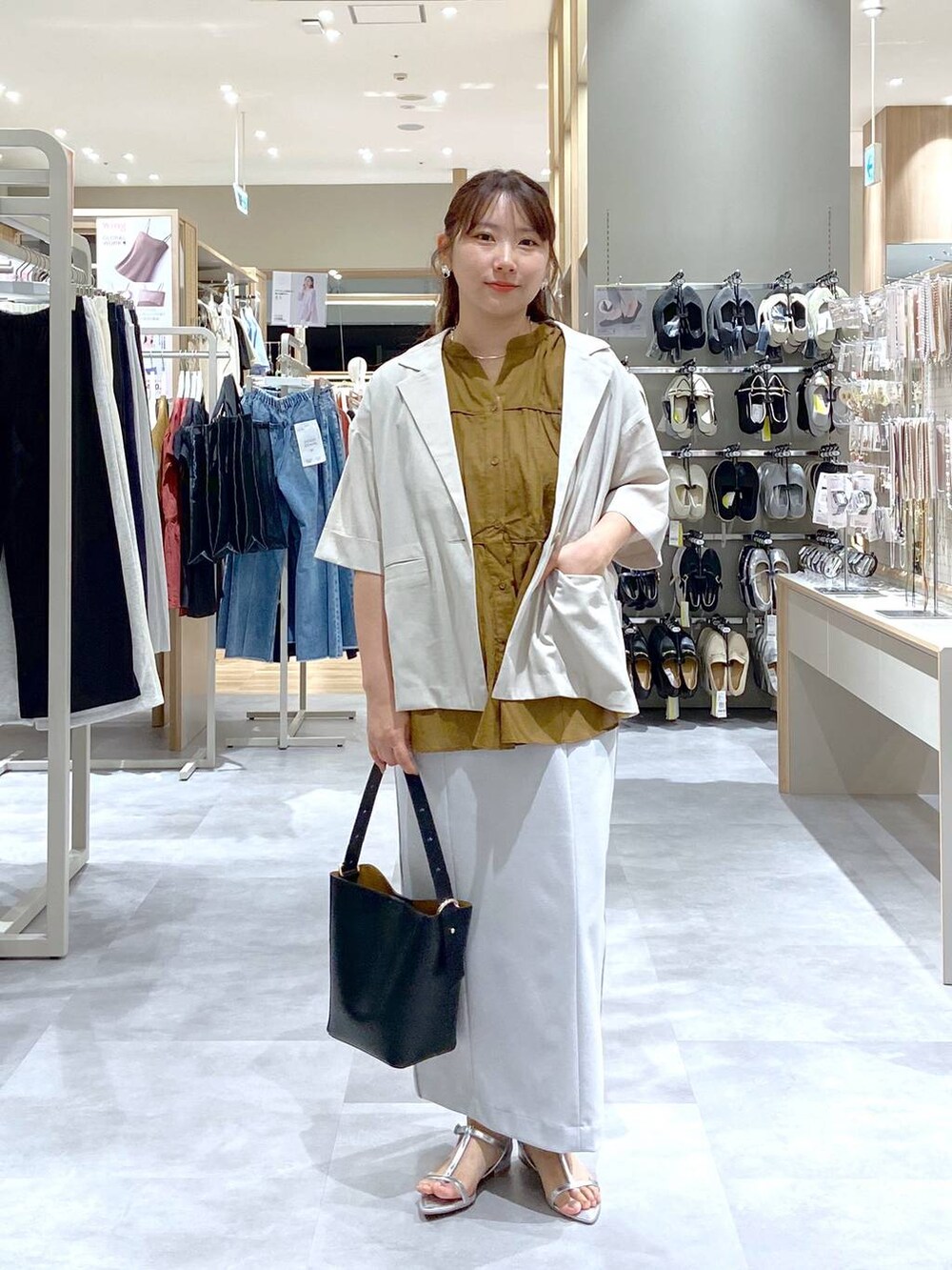 ブラック系のショルダーバッグ、シルバー系のサンダル、グレー系のスカートを着用したレディースの夏コーディネートの2枚目の写真