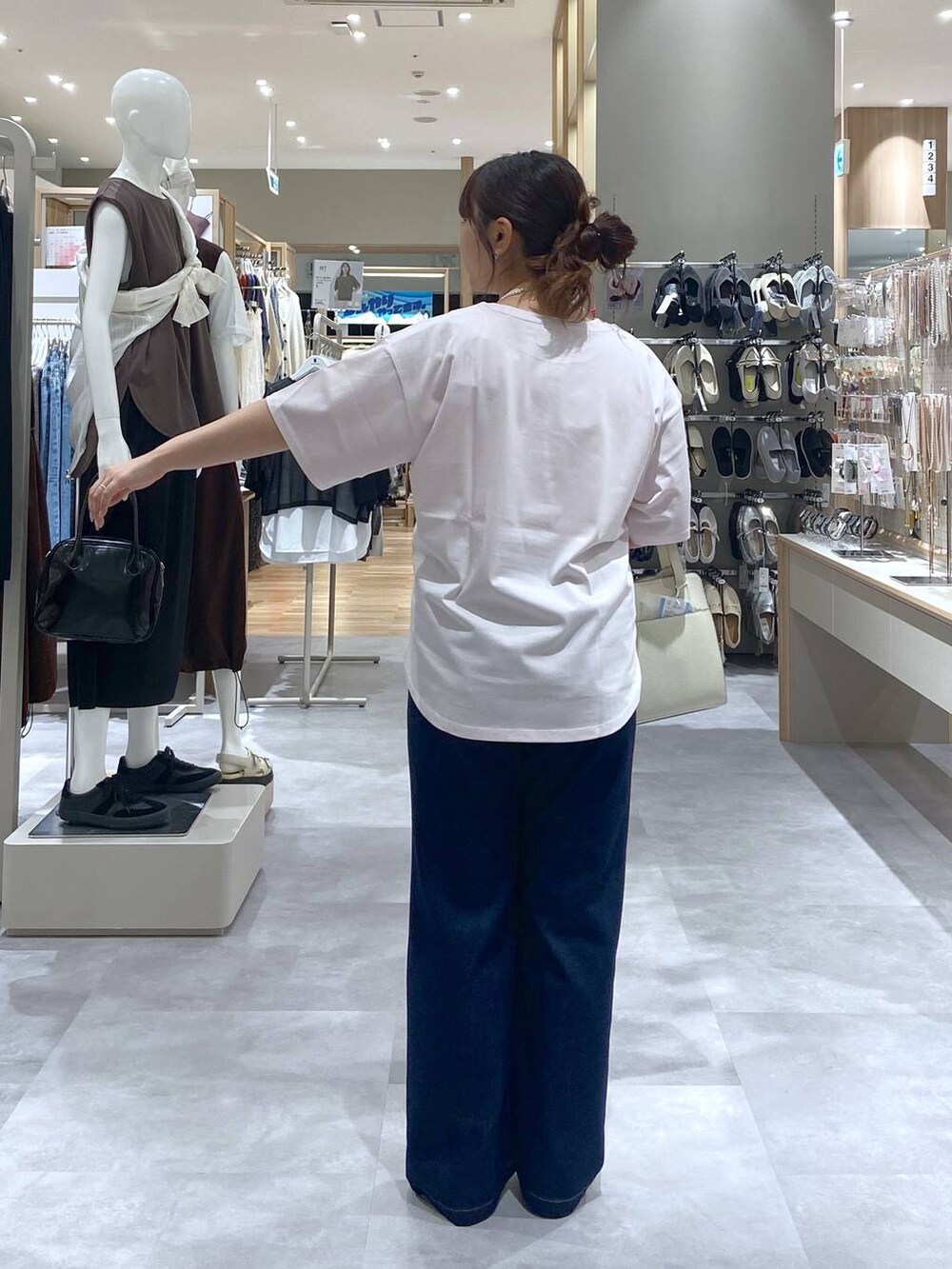 ホワイト系のショルダーバッグ、ピンク系のTシャツ/カットソー、ブルー系のデニムパンツを着用したレディースの夏コーディネートの3枚目の写真