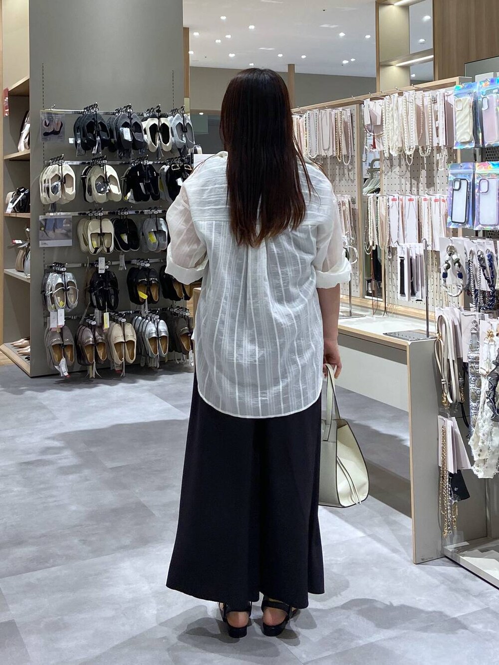 ホワイト系のショルダーバッグ、ホワイト系のシャツ/ブラウス、ブラック系のサンダルを着用したレディースの夏コーディネートの3枚目の写真