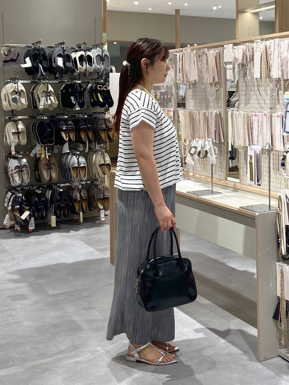 ブラック系のボストンバッグ、シルバー系のサンダル、ホワイト系のTシャツ/カットソーを着用したレディースの夏コーディネートの4枚目の写真