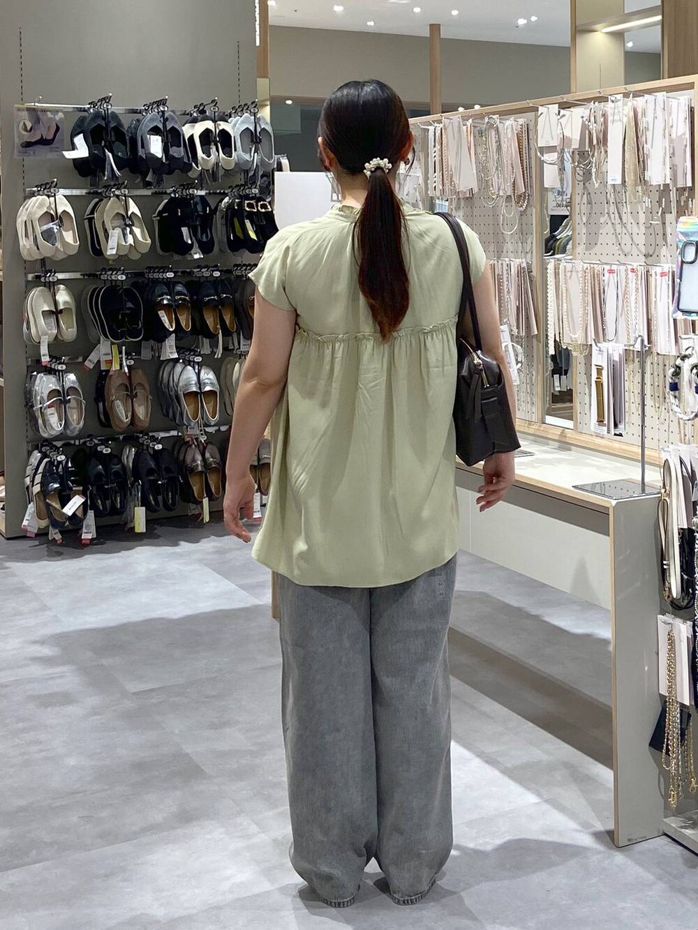 グレー系のデニムパンツ、シルバー系のサンダル、ブラウン系のボストンバッグを着用したレディースの夏コーディネートの3枚目の写真