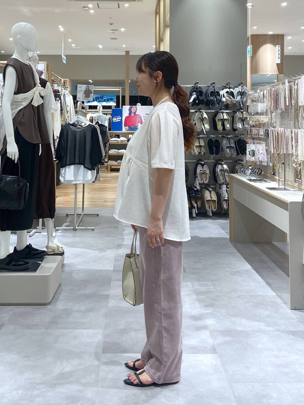 ホワイト系のショルダーバッグ、ベージュ系のTシャツ/カットソー、ブラック系のサンダルを着用したレディースの夏コーディネートの2枚目の写真