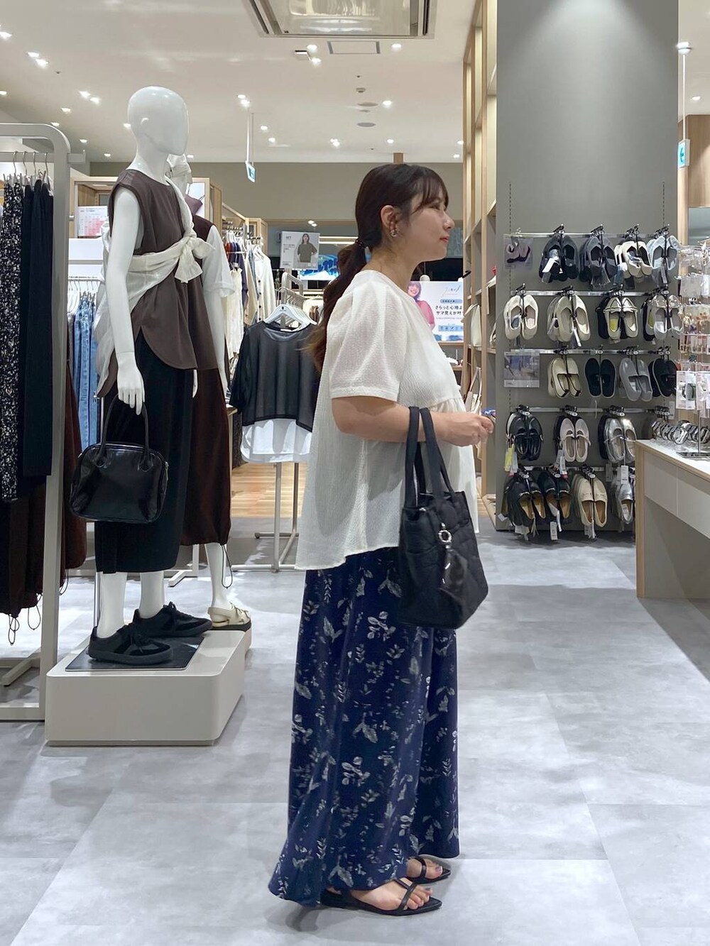 ブラック系のトートバッグ、ベージュ系のTシャツ/カットソー、ブラック系のサンダルを着用したレディースの夏コーディネートの4枚目の写真