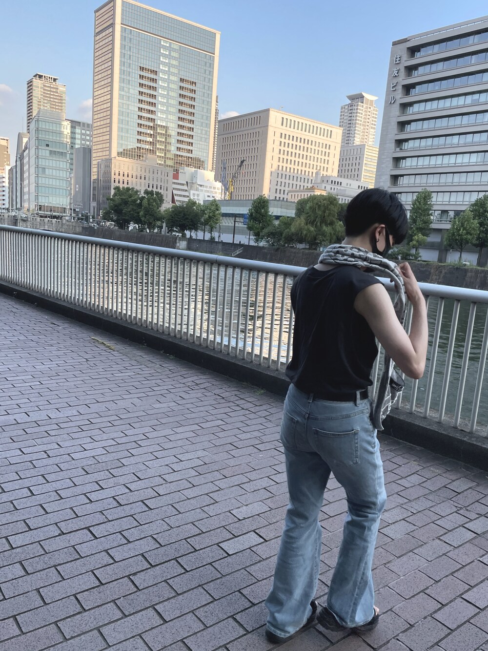 ブルー系のデニムパンツ、ブラック系のタンクトップを着用したレディースの春コーディネートの2枚目の写真