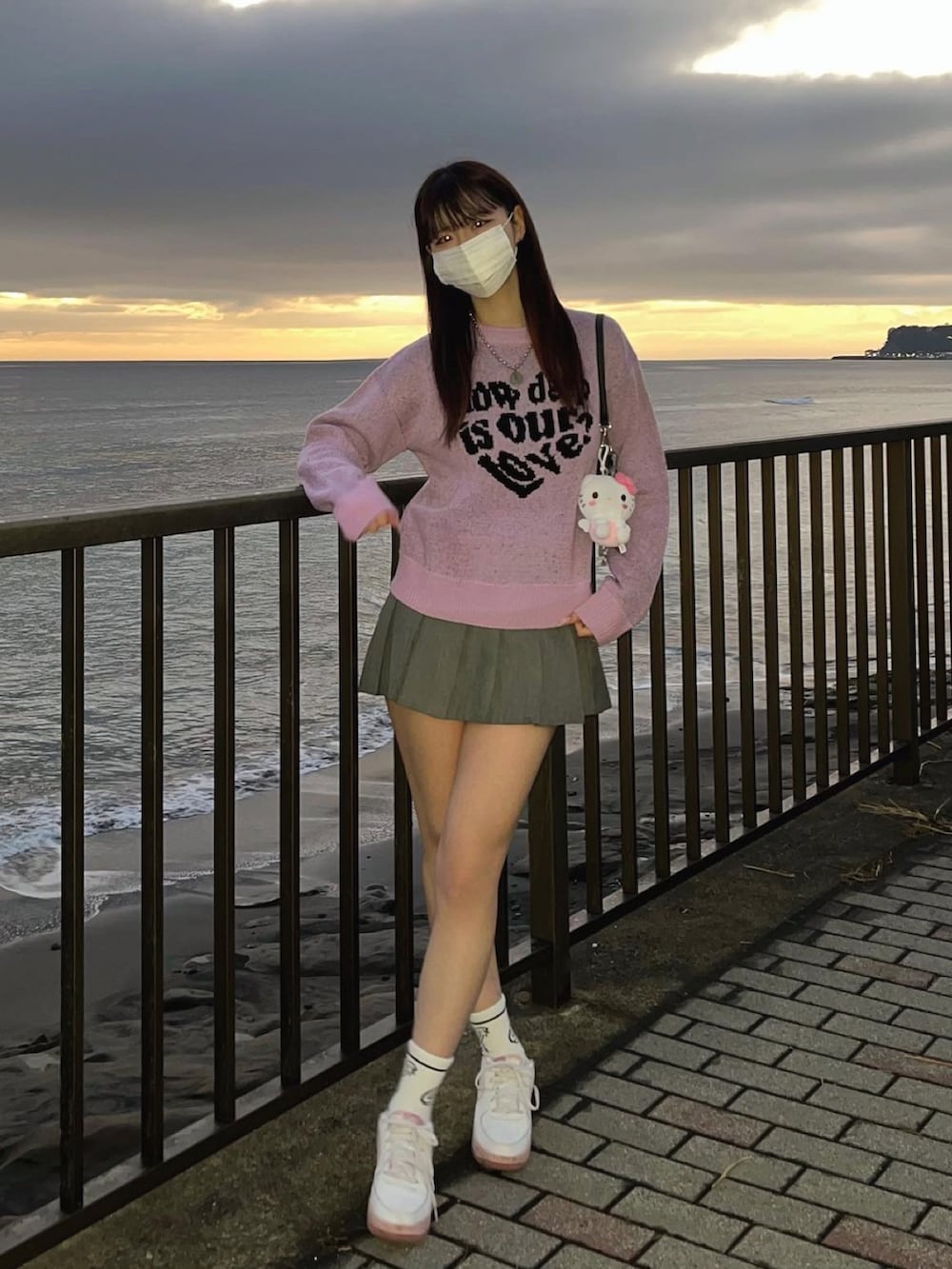 パープル系のニット/セーター、グレー系のスカート、ピンク系のスニーカーを着用したレディースの冬コーディネートの2枚目の写真