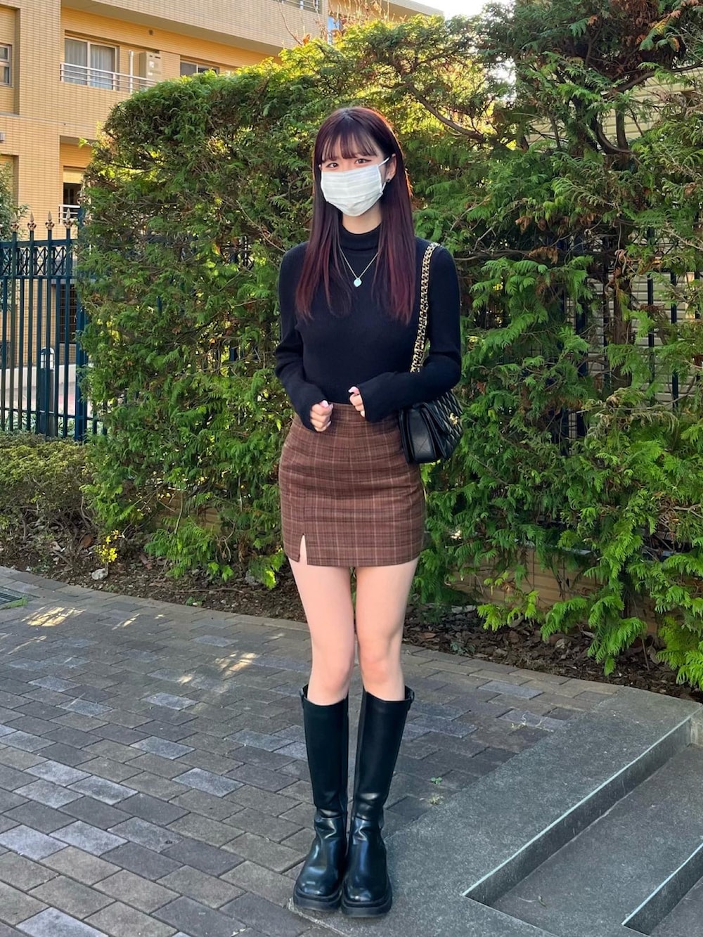 グレー系のニット/セーター、ブラック系のバッグ、ブラック系のブーツを着用したレディースの冬コーディネートの2枚目の写真