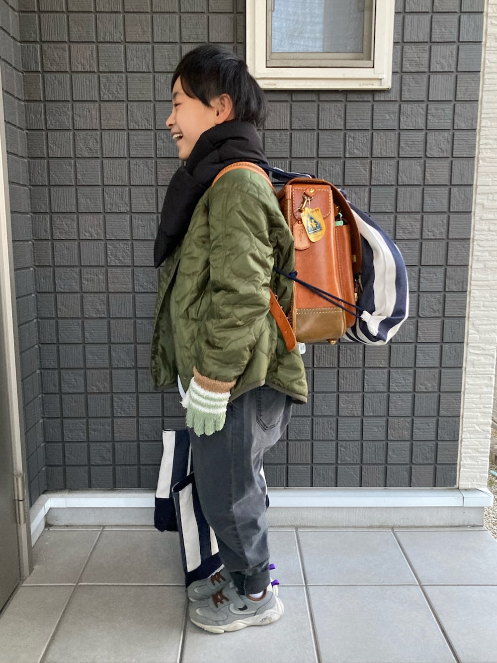 グリーン系のその他アウター、ブラウン系のスウェット、グレー系のデニムパンツを着用したキッズの冬コーディネートの2枚目の写真