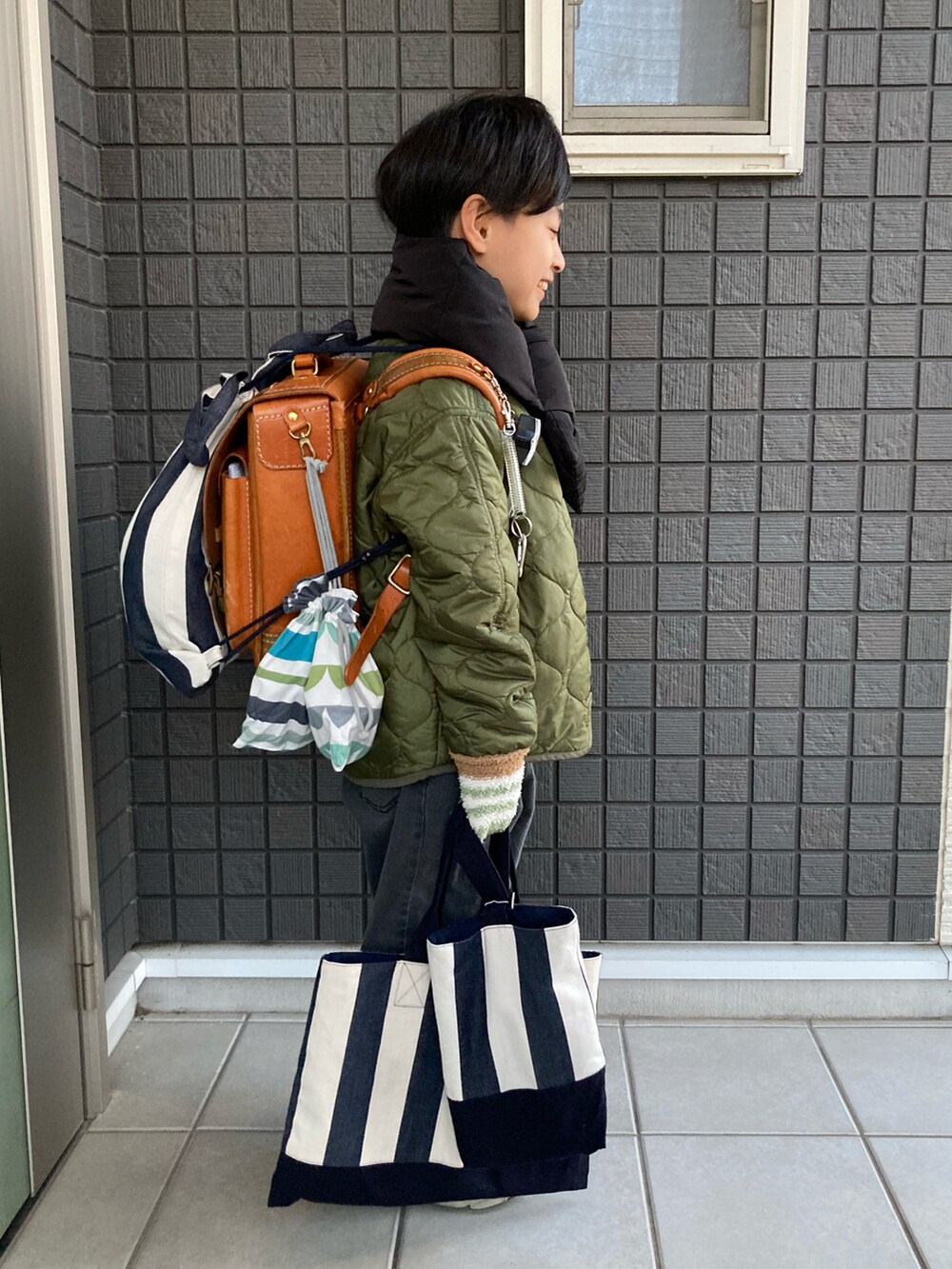 グリーン系のその他アウター、ブラウン系のスウェット、グレー系のデニムパンツを着用したキッズの冬コーディネートの3枚目の写真