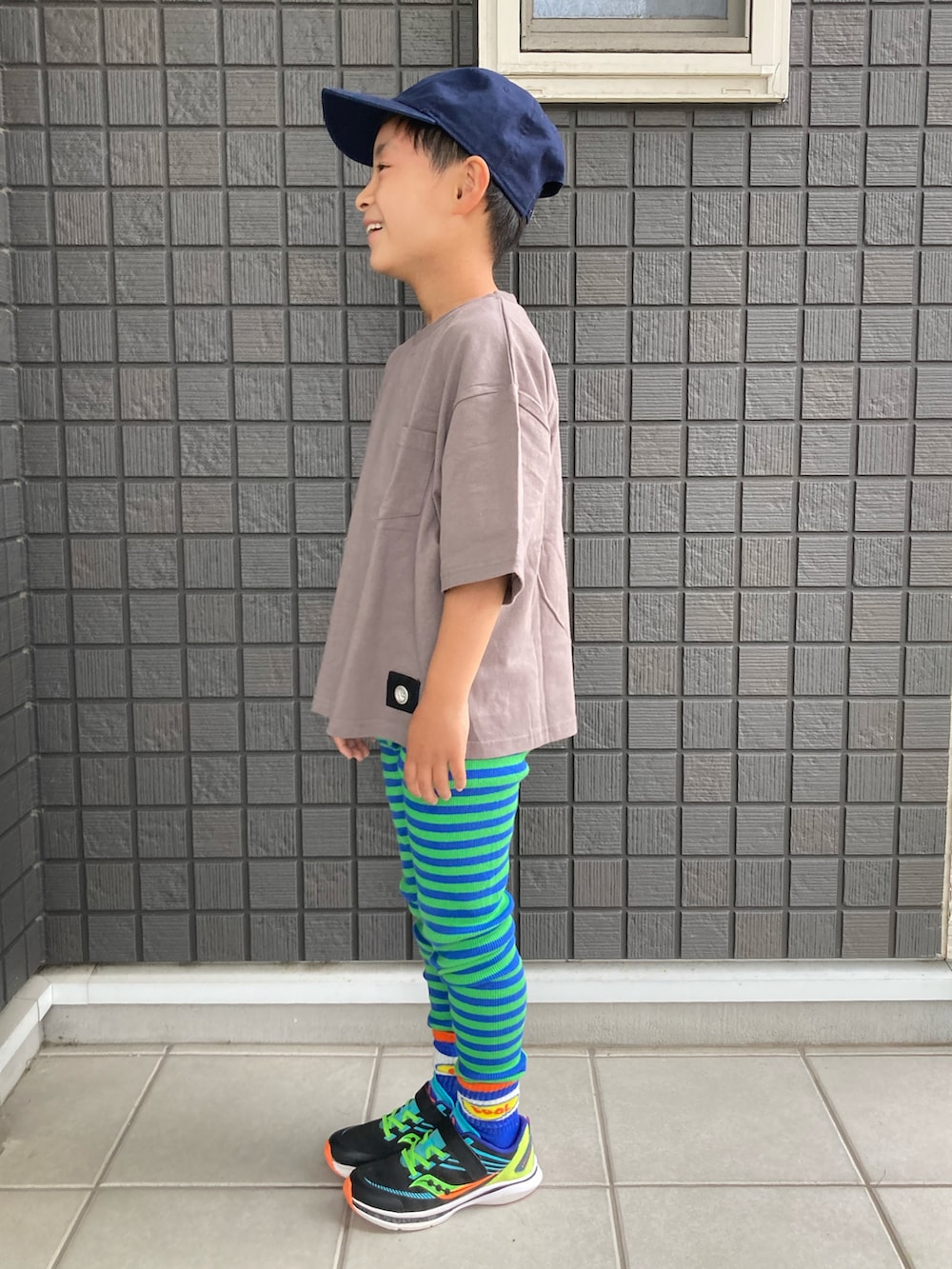 グレー系のTシャツ/カットソー、グリーン系のタンクトップ、ブラック系のスニーカーを着用したキッズの春コーディネートの2枚目の写真