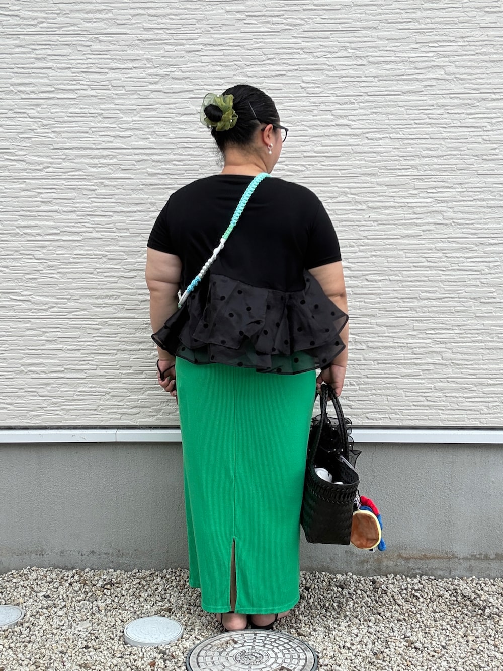ブラック系のハンドバッグ、グリーン系のスカート、ブラック系のサンダルを着用したレディースの夏コーディネートの4枚目の写真