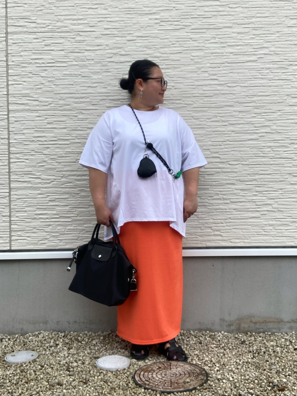 ブラック系のサンダル、ホワイト系のTシャツ/カットソー、オレンジ系のスカートを着用したレディースの夏コーディネートの5枚目の写真