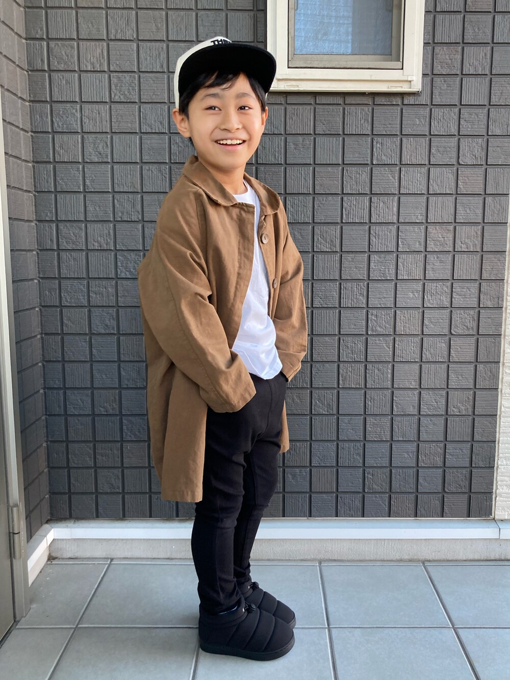 ホワイト系のTシャツ/カットソー、ブラック系のその他パンツ、ブラック系のブーツを着用したキッズの秋コーディネートの4枚目の写真