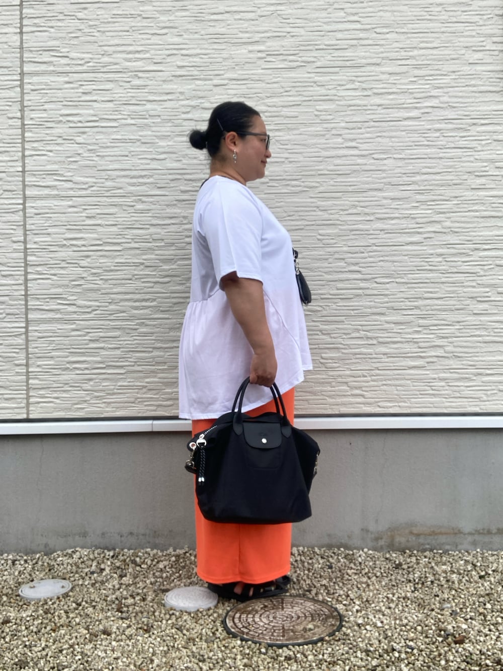 ブラック系のサンダル、ホワイト系のTシャツ/カットソー、オレンジ系のスカートを着用したレディースの夏コーディネートの3枚目の写真