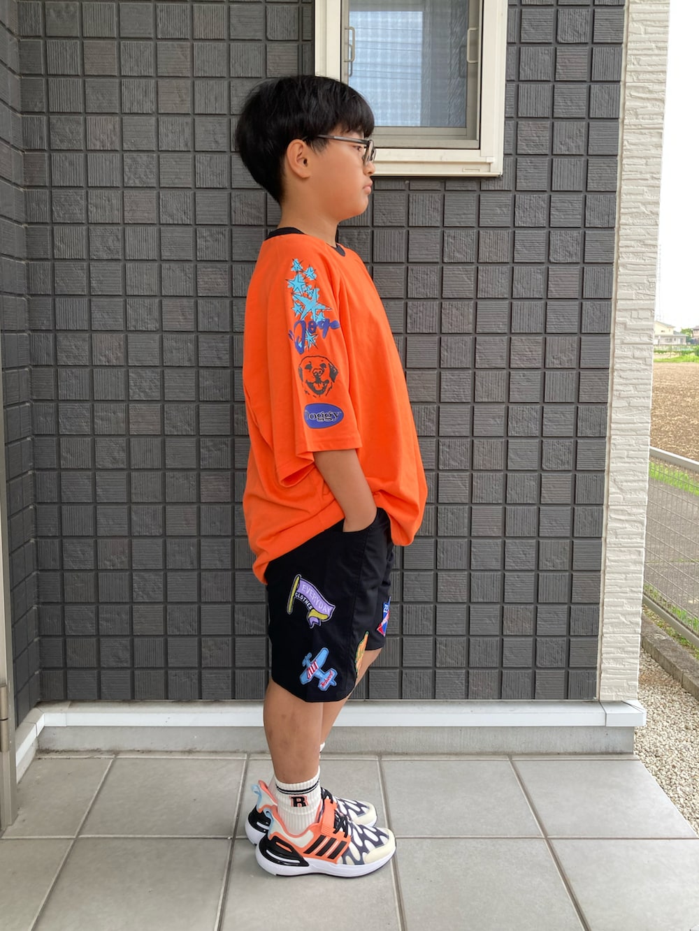 オレンジ系のTシャツ/カットソー、ブラック系のその他パンツ、ブラック系のスニーカーを着用したキッズの夏コーディネートの3枚目の写真