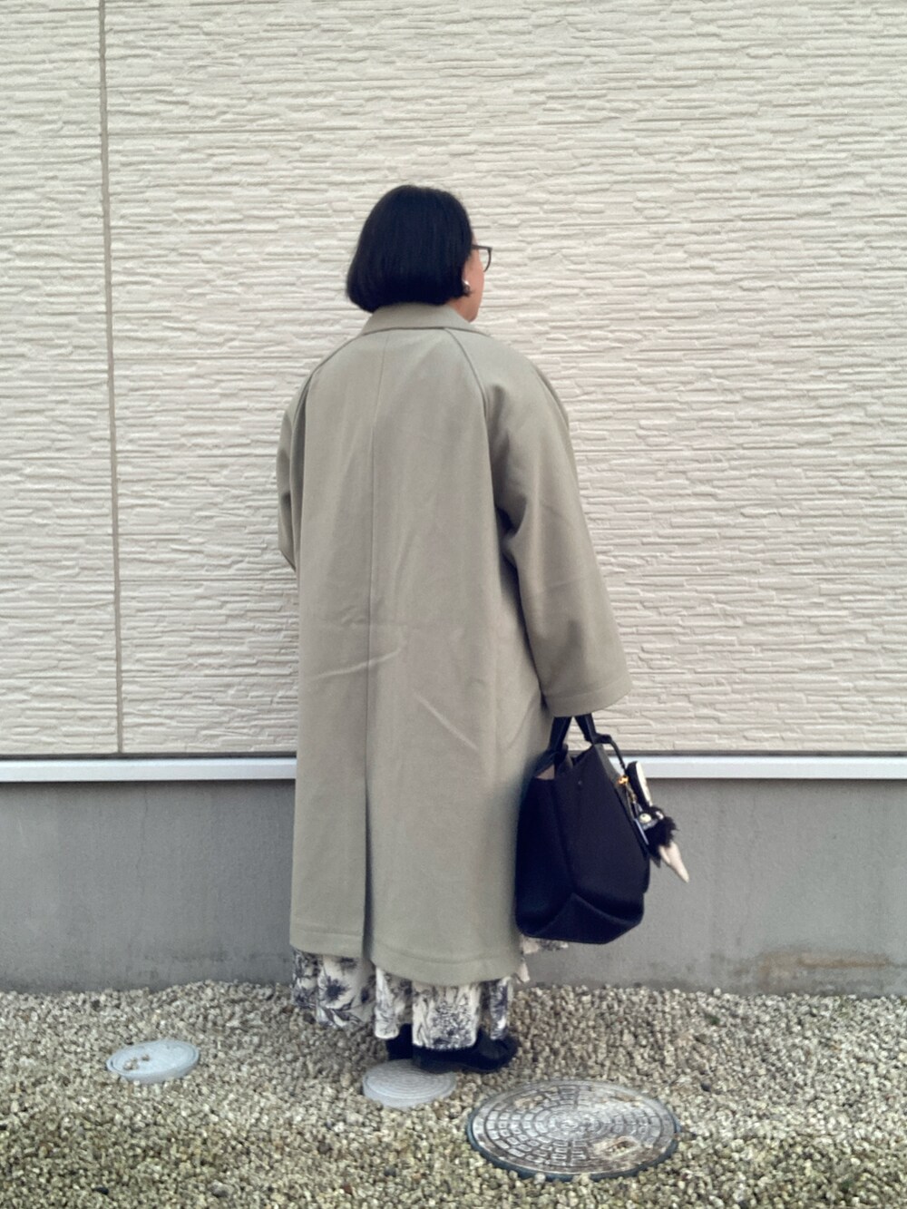 グリーン系のステンカラーコート、ホワイト系のシャツワンピース、ブラック系のベストを着用したレディースの冬コーディネートの4枚目の写真