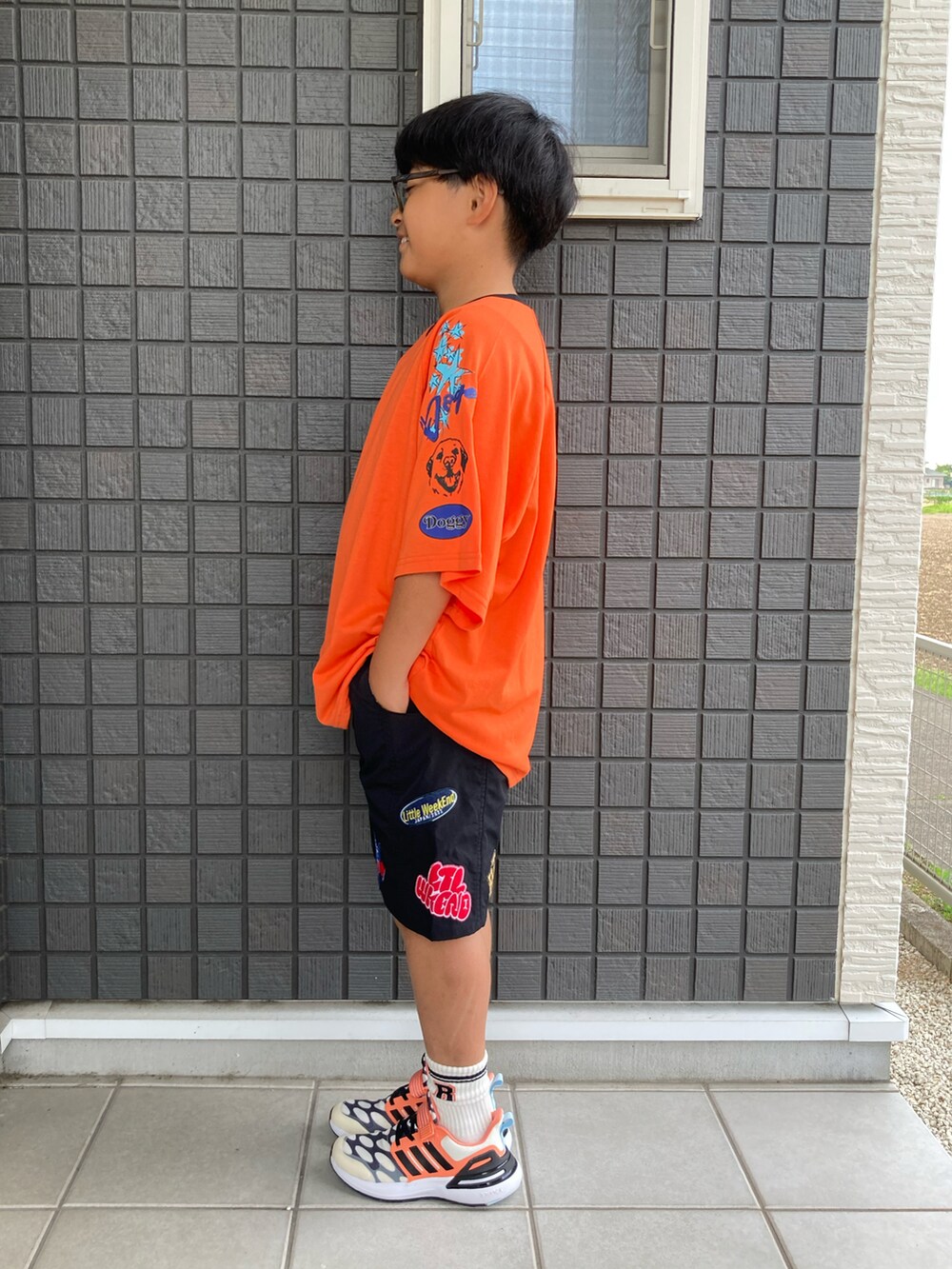 オレンジ系のTシャツ/カットソー、ブラック系のその他パンツ、ブラック系のスニーカーを着用したキッズの夏コーディネートの2枚目の写真