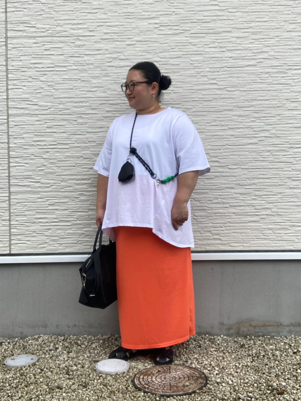 ブラック系のサンダル、ホワイト系のTシャツ/カットソー、オレンジ系のスカートを着用したレディースの夏コーディネートの2枚目の写真