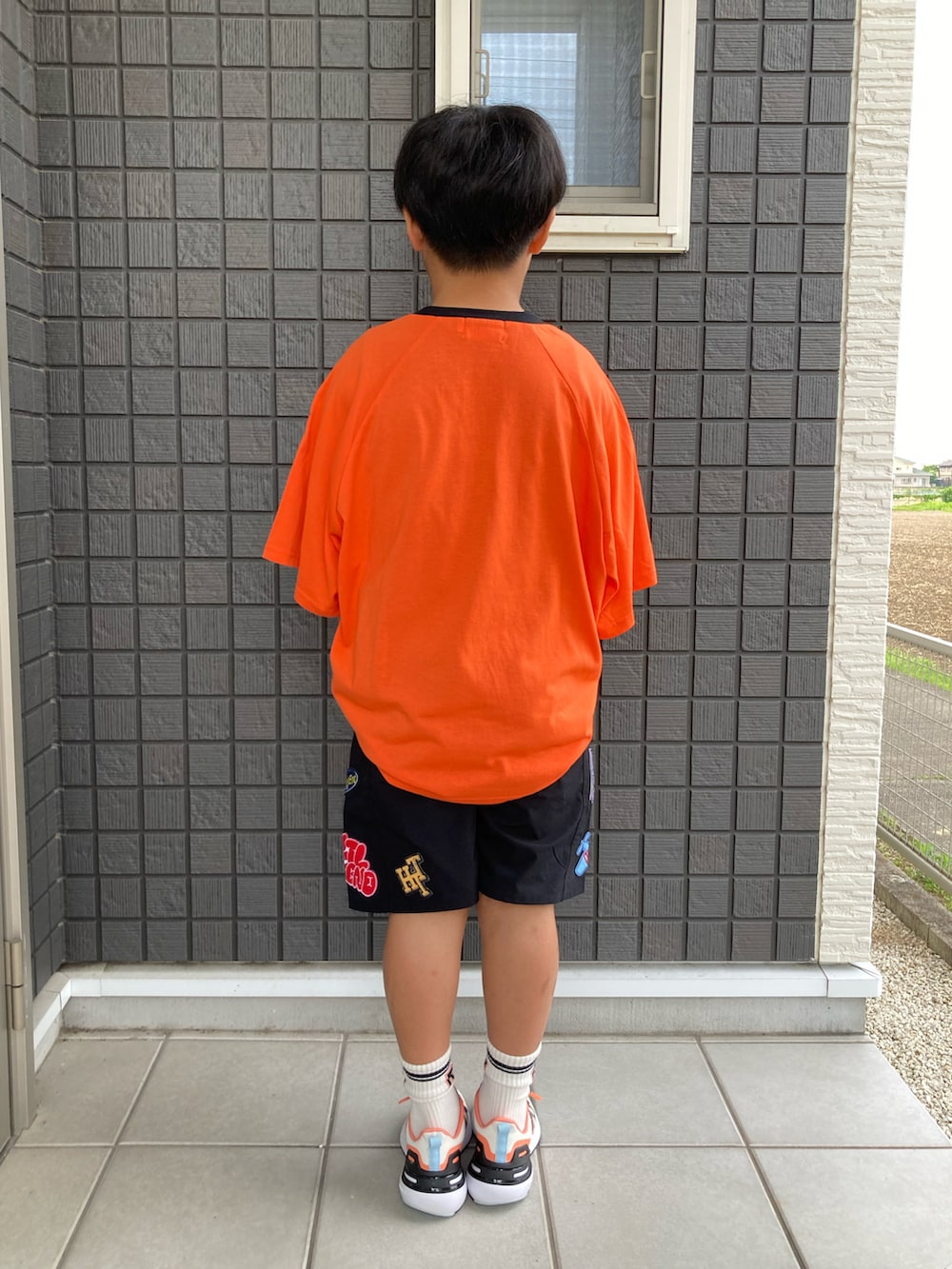 オレンジ系のTシャツ/カットソー、ブラック系のその他パンツ、ブラック系のスニーカーを着用したキッズの夏コーディネートの5枚目の写真