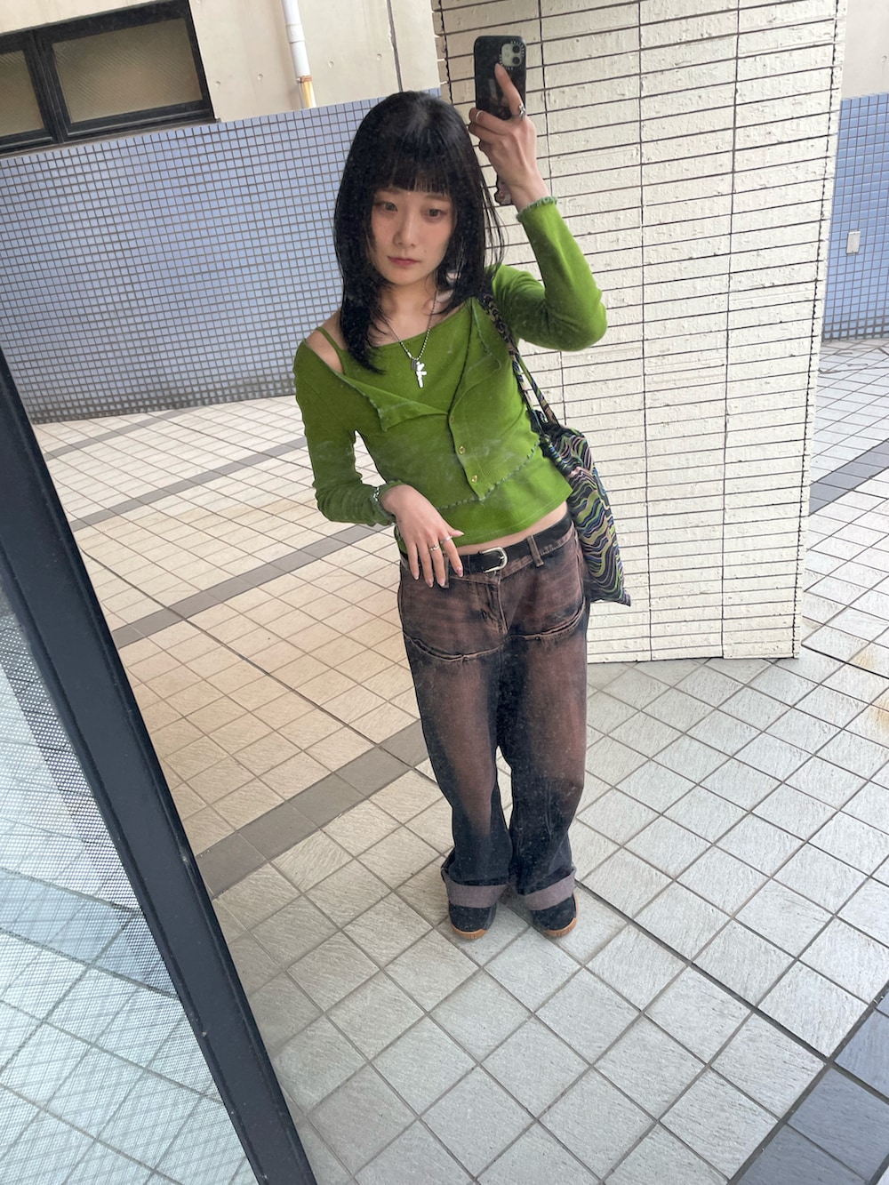 グリーン系のカーディガン/ボレロ、グリーン系のトートバッグ、ブルー系のデニムパンツを着用したレディースの春コーディネートの2枚目の写真