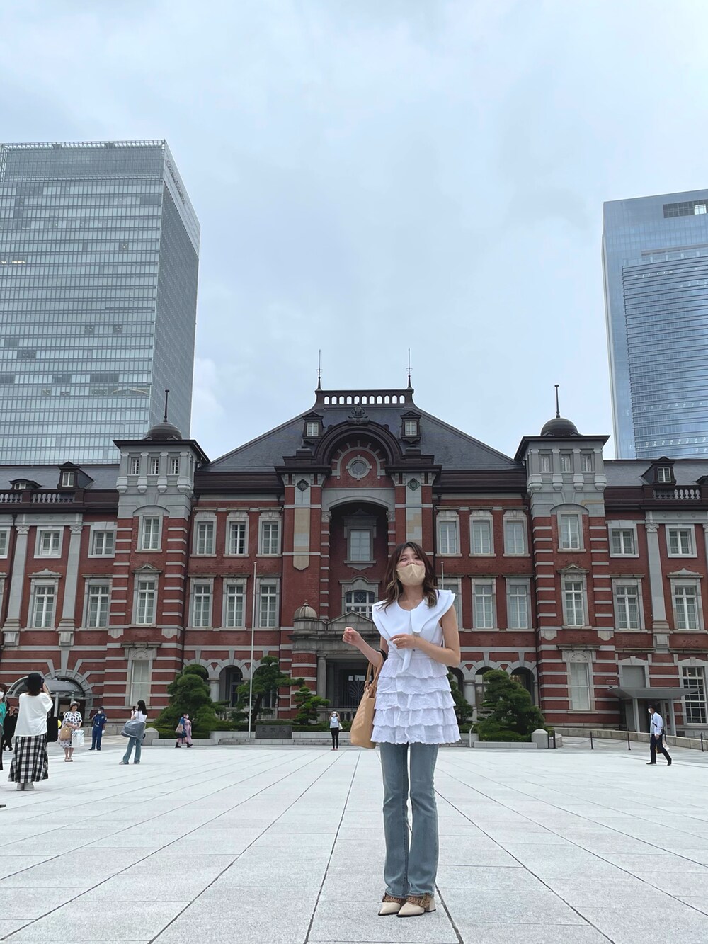 ホワイト系のワンピース、ベージュ系のハンドバッグ、グレー系のデニムパンツを着用したレディースの夏コーディネートの4枚目の写真