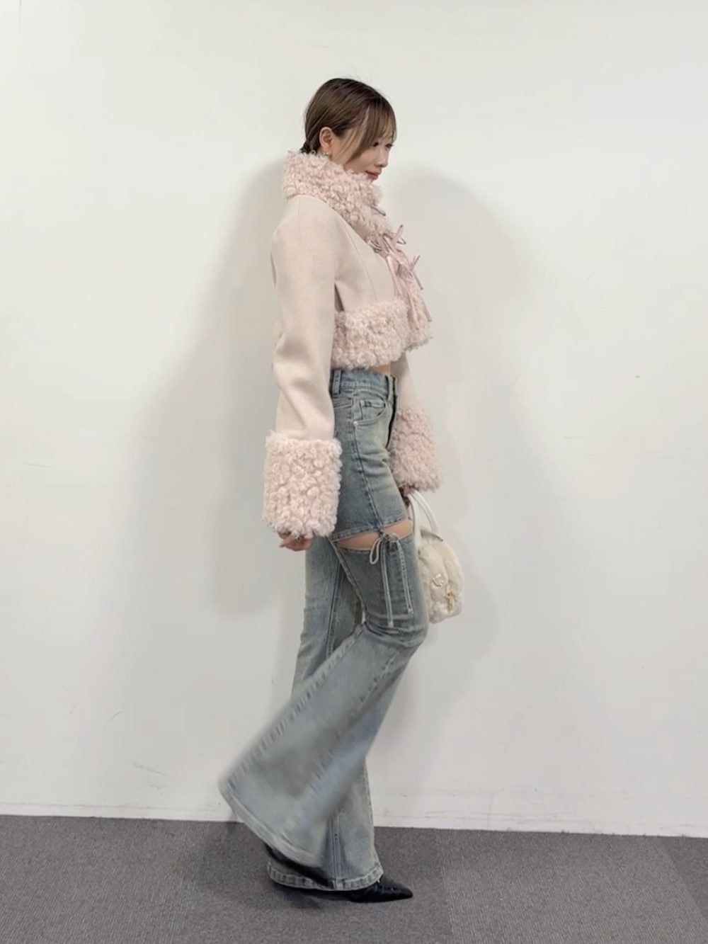 ブルー系のデニムパンツ、ブラック系のパンプス、ホワイト系のハンドバッグを着用したレディースの夏コーディネートの4枚目の写真