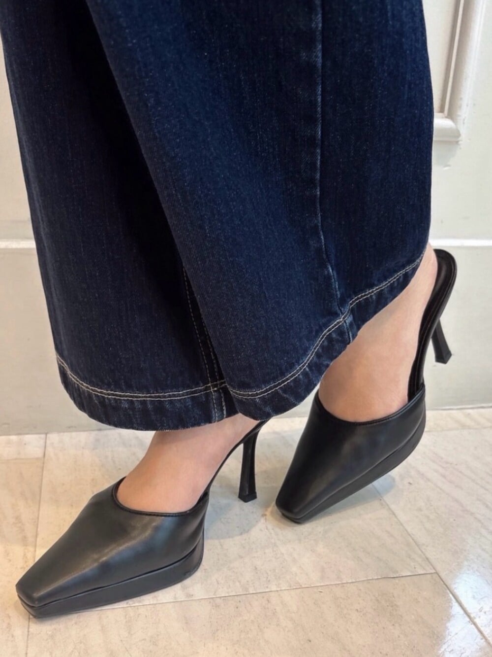 ブラック系のパンプス、ブラック系のハンドバッグ、ブルー系のデニムパンツを着用したレディースの夏コーディネートの6枚目の写真