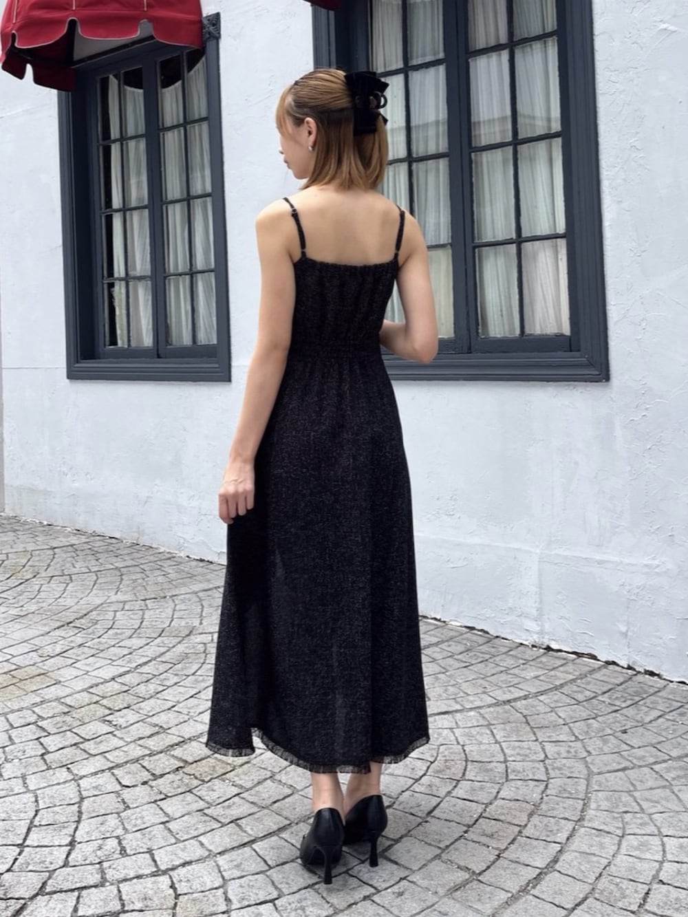 ブラック系のハンドバッグ、ホワイト系のワンピース、ブラック系のパンプスを着用したレディースの夏コーディネートの6枚目の写真