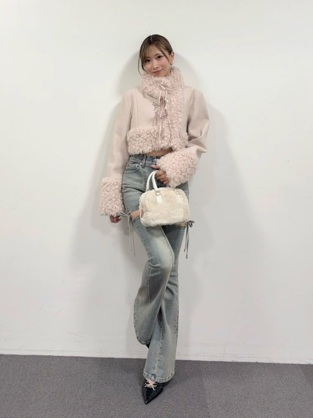 ブルー系のデニムパンツ、ブラック系のパンプス、ホワイト系のハンドバッグを着用したレディースの夏コーディネートの3枚目の写真