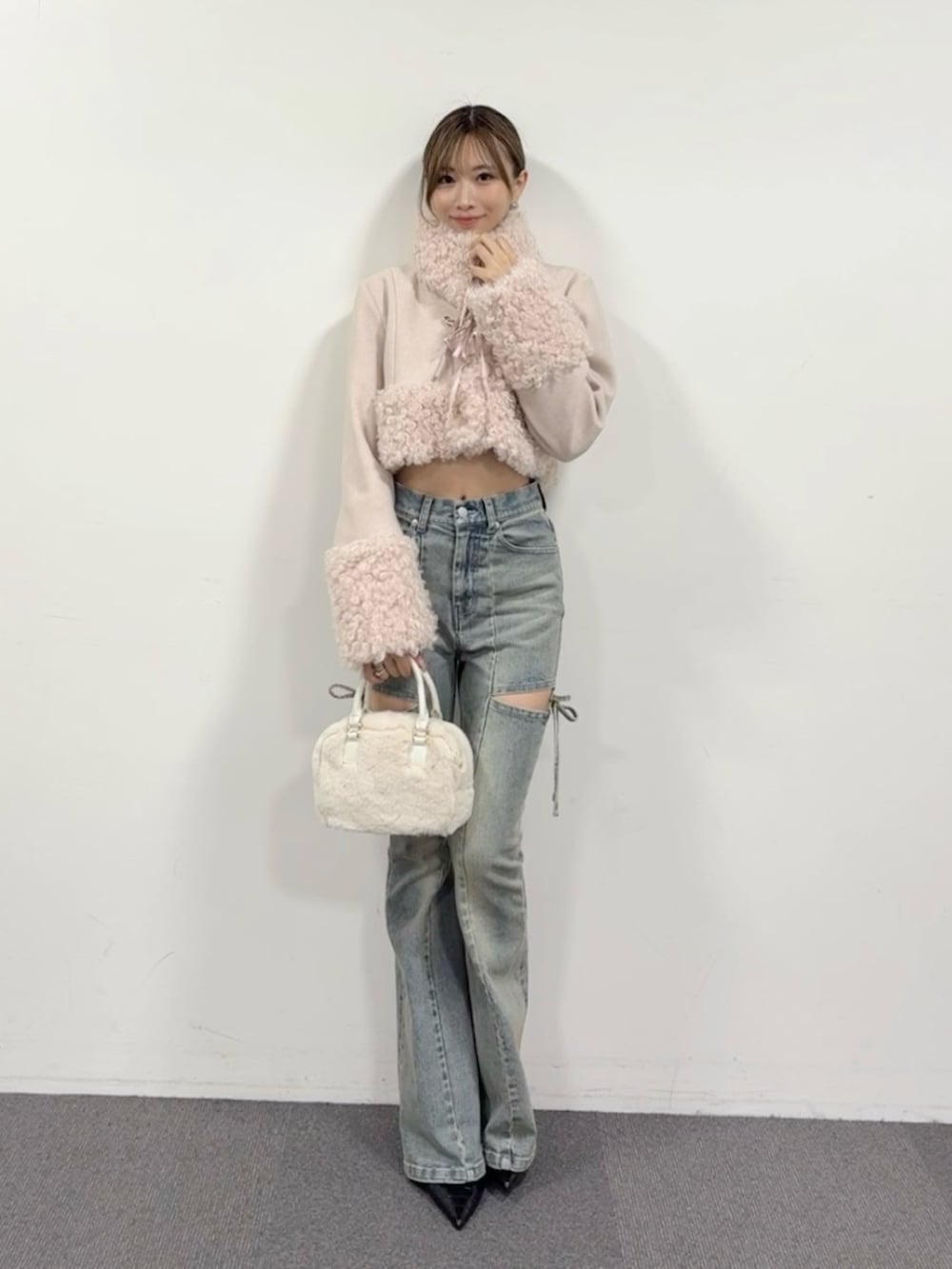 ブルー系のデニムパンツ、ブラック系のパンプス、ホワイト系のハンドバッグを着用したレディースの夏コーディネートの2枚目の写真