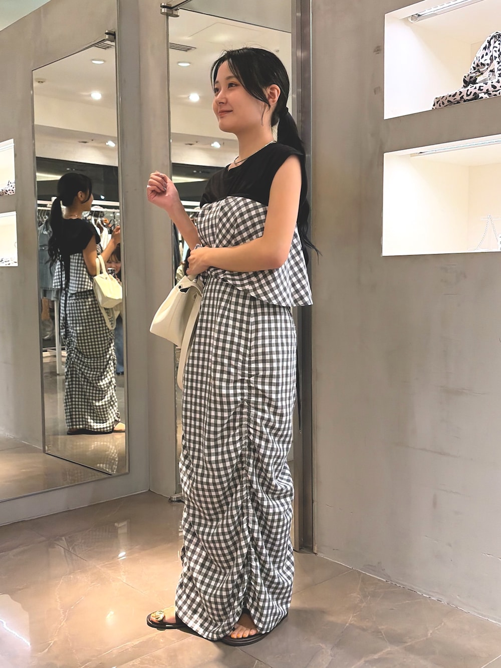 グレー系のスカート、ホワイト系のショルダーバッグ、ブラウン系のサンダルを着用したレディースの夏コーディネートの3枚目の写真