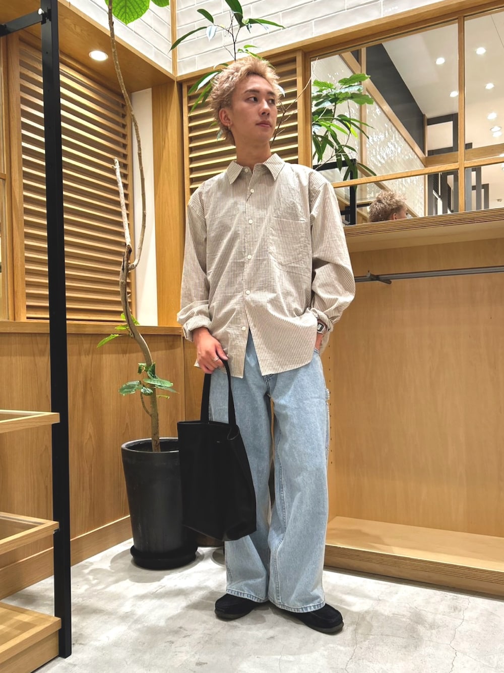 ベージュ系のシャツ/ブラウス、ブルー系のデニムパンツ、ブラック系のトートバッグを着用したメンズの秋コーディネートの3枚目の写真